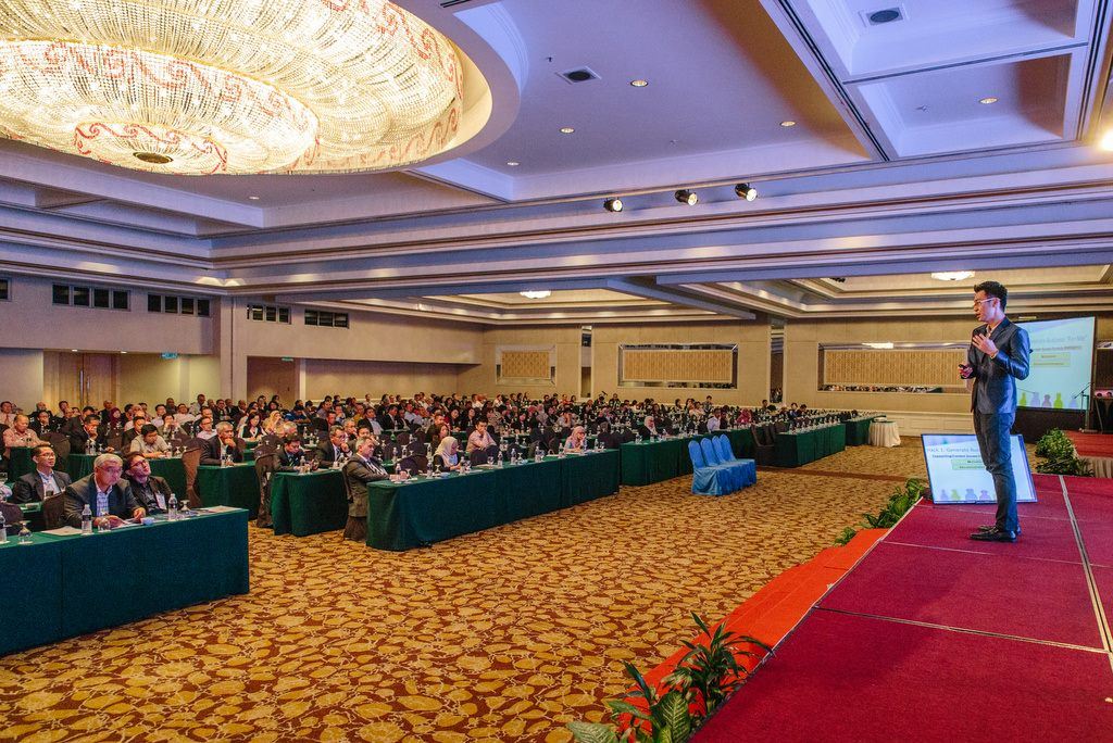 Packed conference hall with Marcus presenting