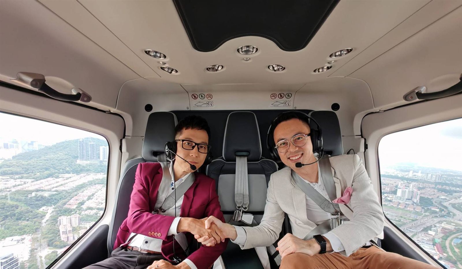 Marcus Teoh shaking hands with a guest inside a private helicopter above Kuala Lumpur
